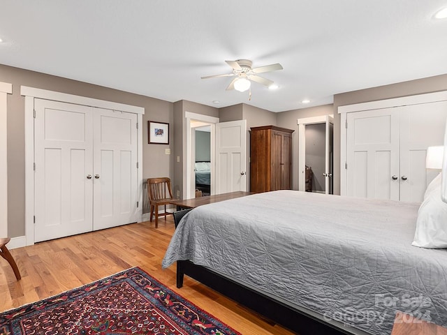 bedroom with ceiling fan, two closets, and hardwood / wood-style floors