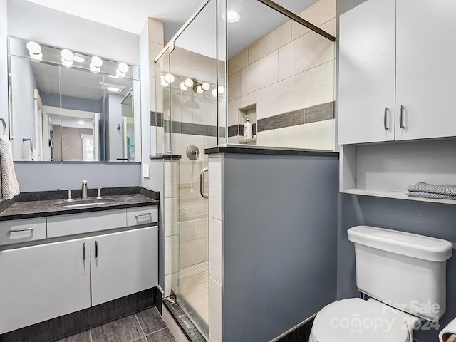 bathroom featuring toilet, a shower with shower door, and vanity