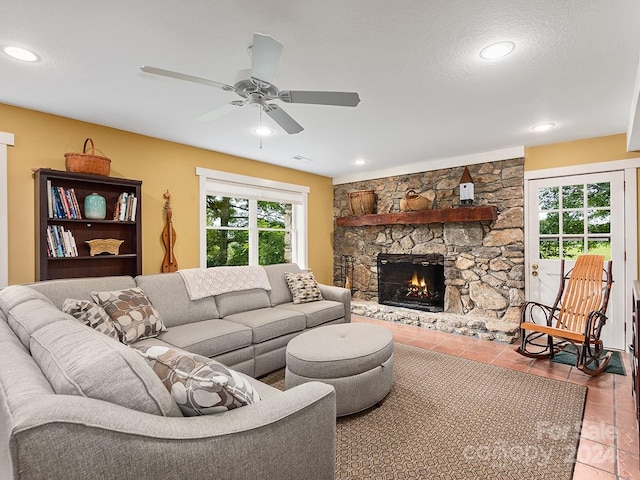 living room with tile patterned floors, a textured ceiling, a fireplace, and ceiling fan