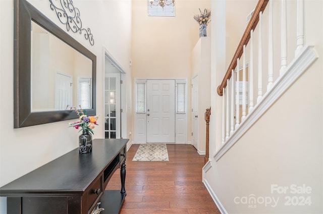 foyer entrance with a towering ceiling and dark wood-type flooring