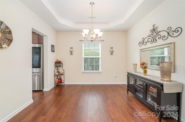 misc room featuring a tray ceiling, dark hardwood / wood-style flooring, and a chandelier