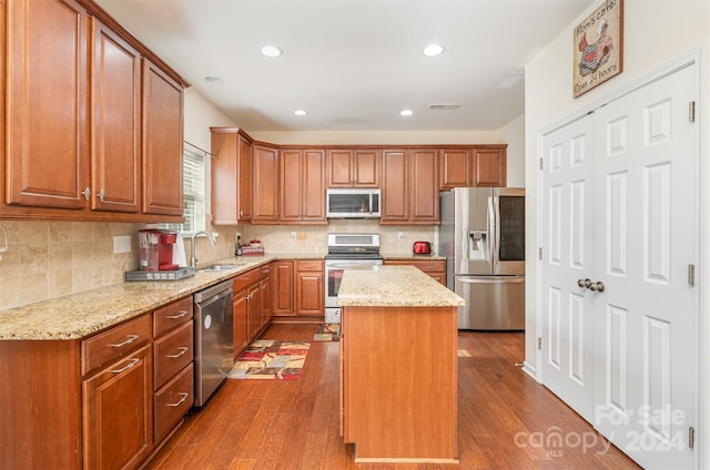 kitchen featuring wood-type flooring, a kitchen island, sink, and stainless steel appliances