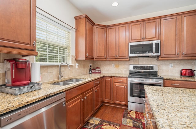 kitchen featuring sink, tasteful backsplash, dark wood-type flooring, appliances with stainless steel finishes, and light stone countertops