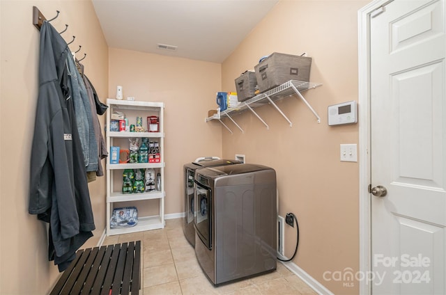 clothes washing area with washer and clothes dryer and light tile patterned floors