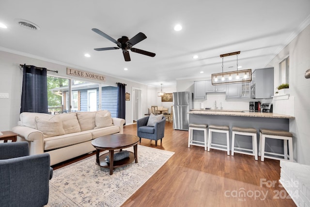 living room with ornamental molding, ceiling fan, dark wood-type flooring, and sink