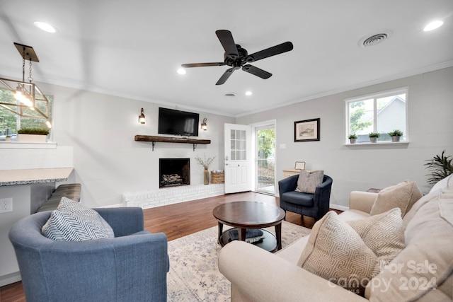 living room featuring a brick fireplace, ceiling fan, dark hardwood / wood-style floors, and crown molding