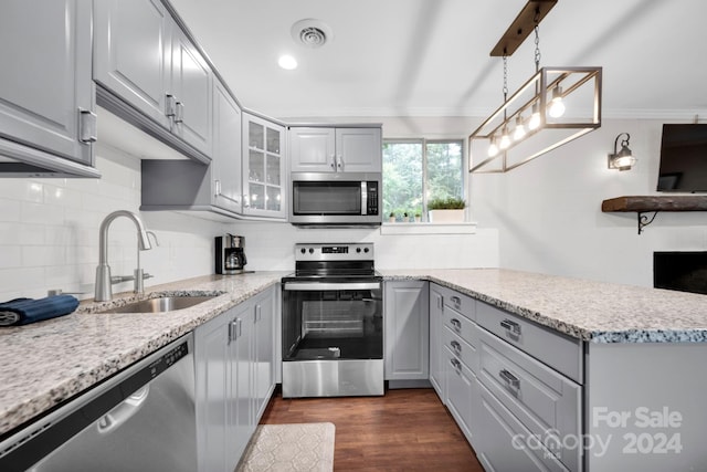 kitchen featuring hanging light fixtures, ornamental molding, sink, stainless steel appliances, and dark hardwood / wood-style floors