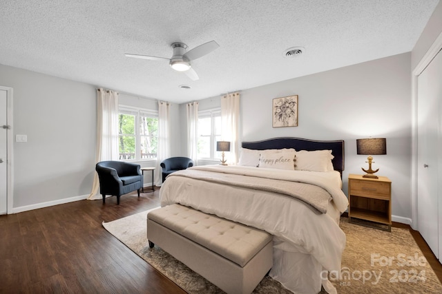 bedroom with a textured ceiling, ceiling fan, and dark wood-type flooring