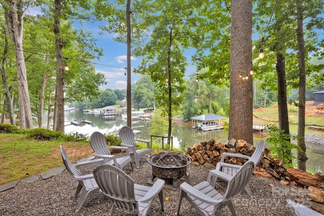 view of patio / terrace featuring a dock, a fire pit, and a water view