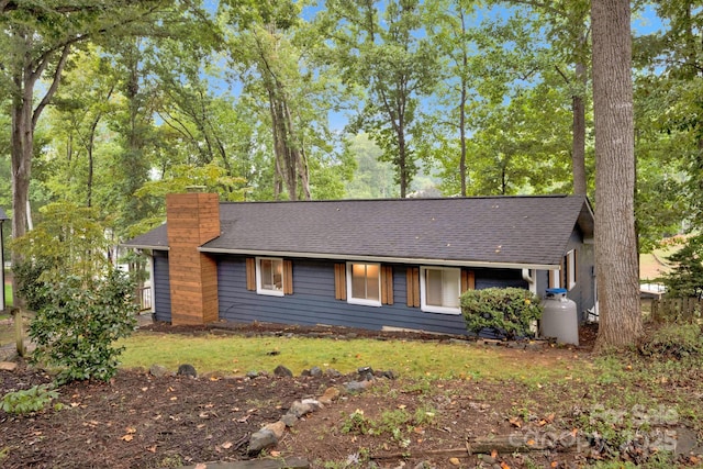 single story home with a chimney, roof with shingles, and a front yard