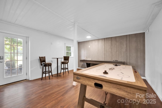 playroom with baseboards, dark wood-type flooring, and wood walls