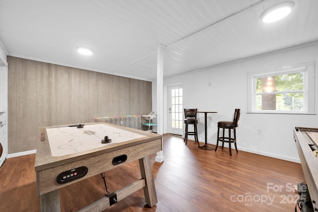 recreation room featuring wooden walls, plenty of natural light, wood finished floors, and baseboards