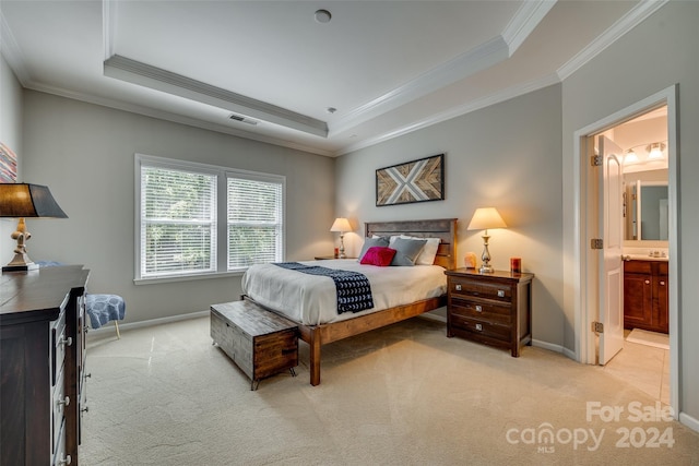 bedroom with light carpet, ornamental molding, a tray ceiling, and ensuite bathroom