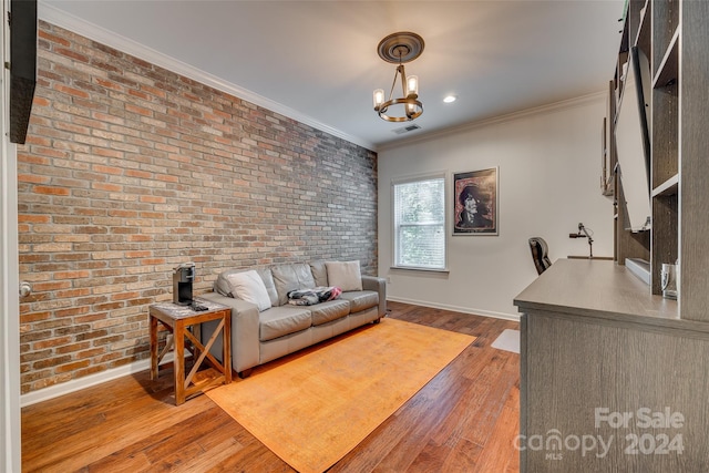 living room featuring ornamental molding, hardwood / wood-style flooring, a notable chandelier, and brick wall