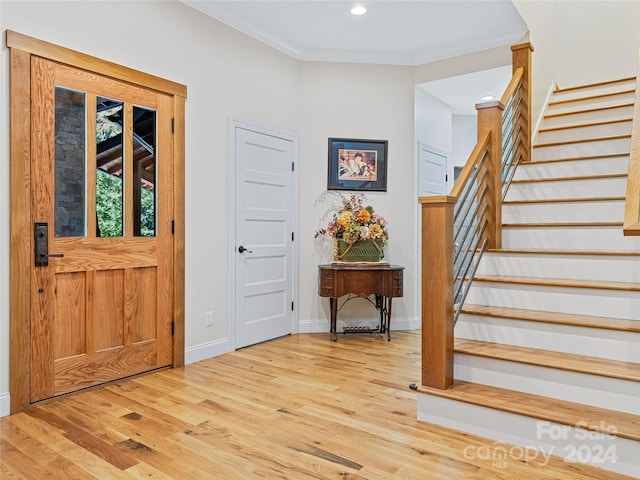 entryway with light hardwood / wood-style floors and crown molding