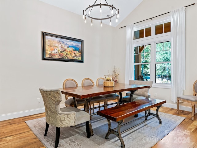 dining room featuring light hardwood / wood-style floors, lofted ceiling, and a chandelier