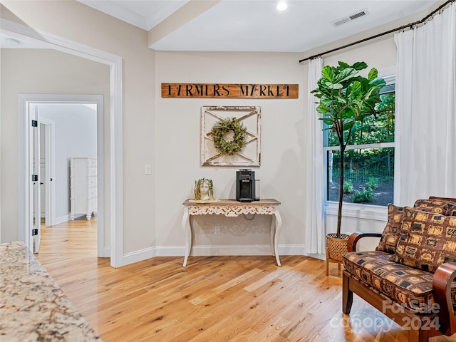 sitting room with ornamental molding and hardwood / wood-style floors