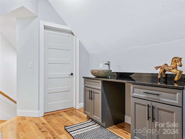 bathroom with vanity, hardwood / wood-style flooring, and vaulted ceiling