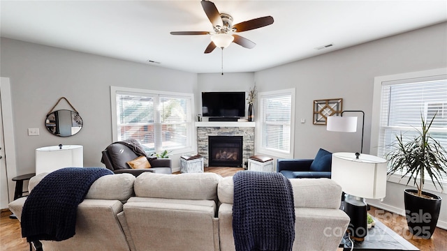 living room featuring visible vents, light wood-type flooring, a ceiling fan, and a healthy amount of sunlight