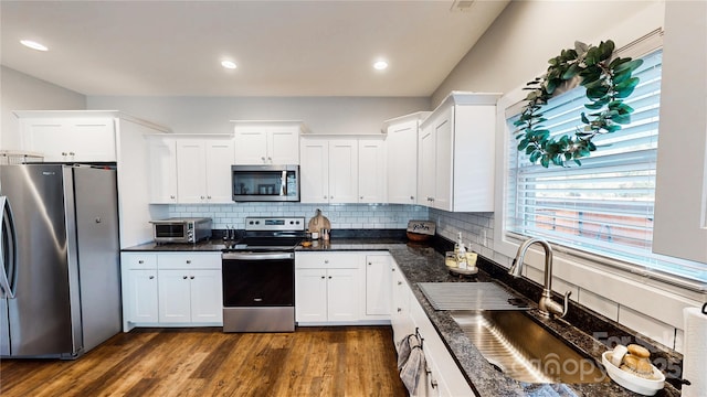 kitchen featuring stainless steel appliances, dark wood-style flooring, white cabinets, and decorative backsplash