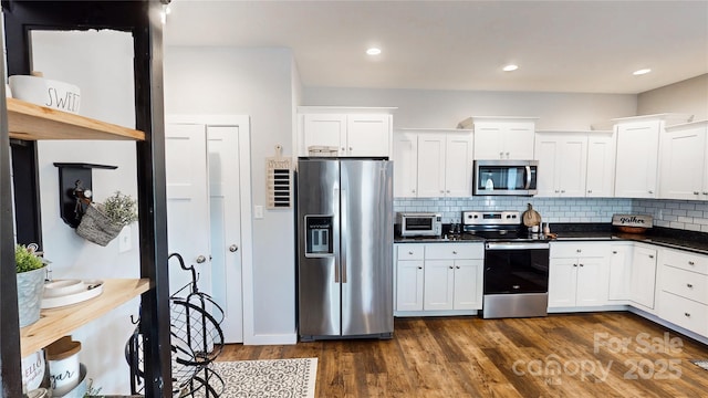 kitchen featuring backsplash, white cabinets, appliances with stainless steel finishes, dark countertops, and dark wood-style floors