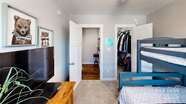 bedroom with a closet, baseboards, a walk in closet, and carpet flooring