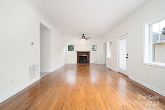 unfurnished living room with light hardwood / wood-style floors, ornamental molding, and ceiling fan