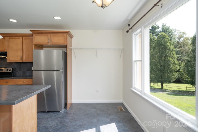 kitchen with backsplash, exhaust hood, plenty of natural light, and stainless steel refrigerator