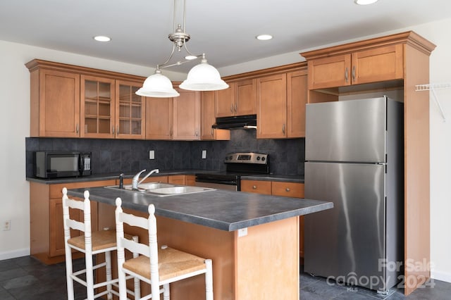 kitchen featuring backsplash, appliances with stainless steel finishes, a kitchen island with sink, pendant lighting, and sink