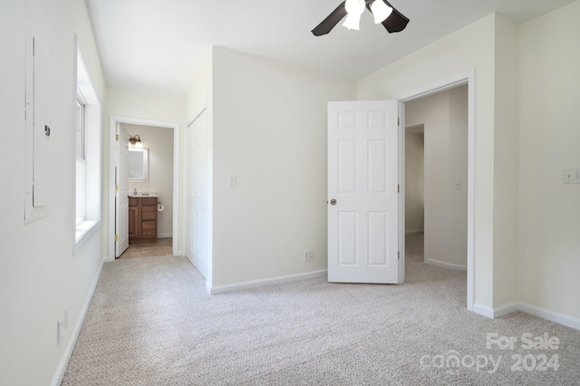 unfurnished bedroom featuring connected bathroom, light carpet, and ceiling fan