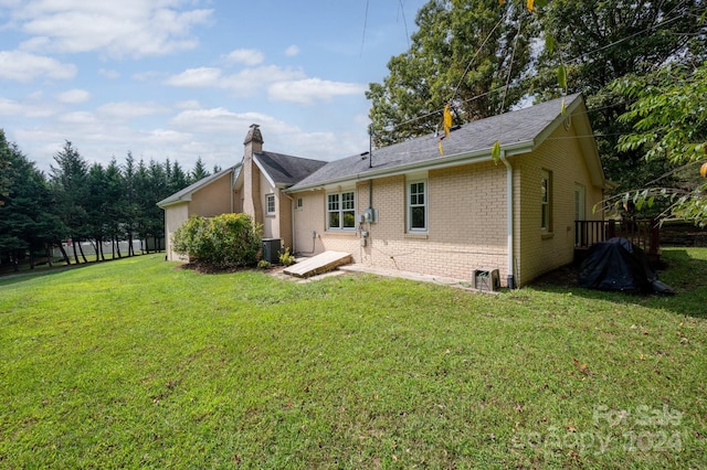 rear view of property featuring a yard and central AC unit