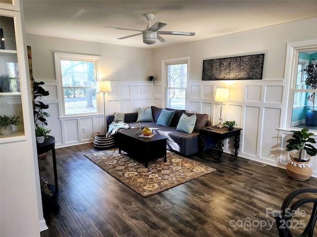 living room featuring dark wood-style flooring, a wealth of natural light, and a decorative wall