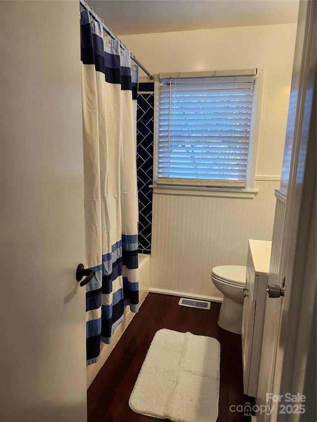 full bathroom with a wainscoted wall, visible vents, shower / tub combo, vanity, and wood finished floors