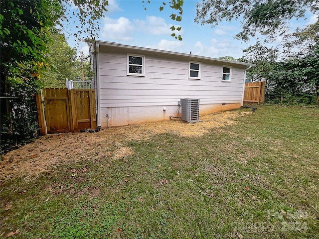 rear view of house with a lawn and central AC