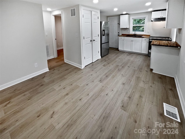 kitchen with white cabinets, appliances with stainless steel finishes, light hardwood / wood-style floors, and wood counters