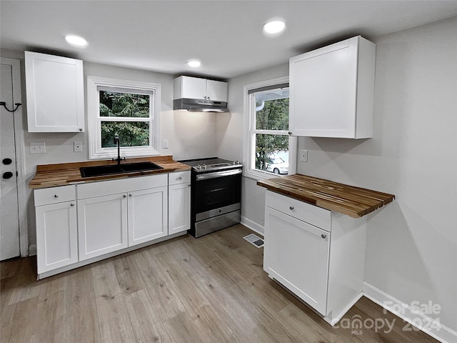 kitchen featuring butcher block countertops, white cabinetry, a healthy amount of sunlight, and stainless steel electric range