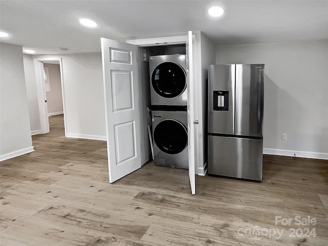 laundry area with light hardwood / wood-style floors and stacked washer / dryer