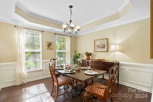 dining room with dark wood-type flooring, a tray ceiling, a chandelier, and crown molding