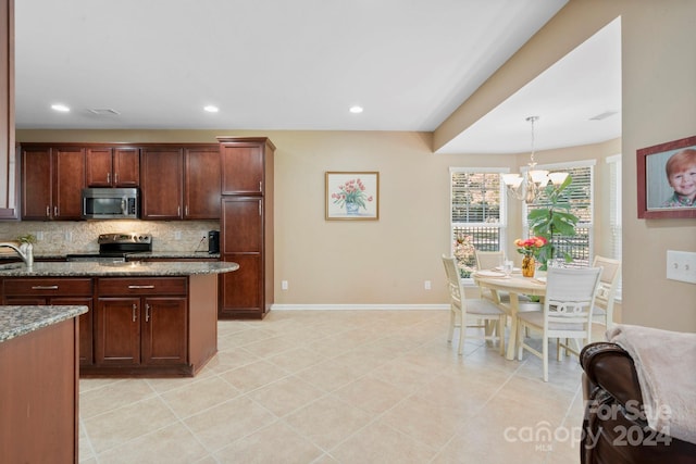 kitchen featuring light stone counters, an inviting chandelier, decorative backsplash, hanging light fixtures, and appliances with stainless steel finishes