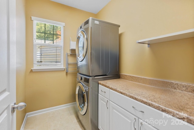 washroom featuring stacked washer and clothes dryer and cabinets