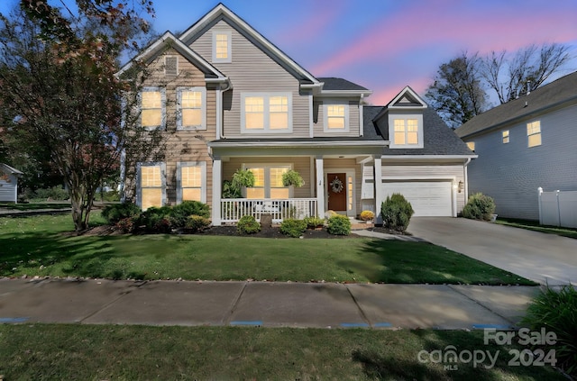 view of front of property with a garage, covered porch, and a lawn