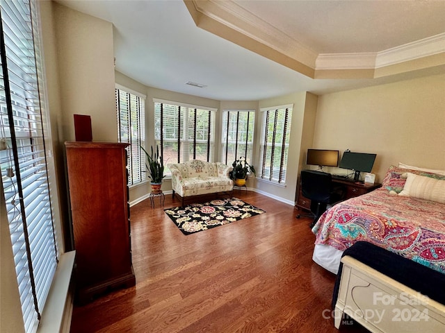 bedroom featuring ornamental molding, dark hardwood / wood-style floors, and a tray ceiling