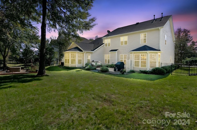 back house at dusk featuring a yard