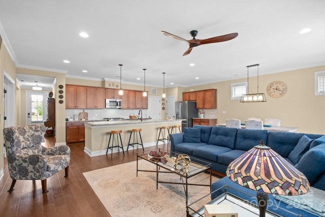 living room with ceiling fan, sink, dark wood-type flooring, and ornamental molding