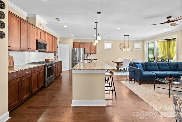 kitchen with decorative backsplash, a breakfast bar, stainless steel appliances, sink, and an island with sink