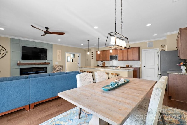 dining room with hardwood / wood-style floors, ceiling fan, ornamental molding, and sink