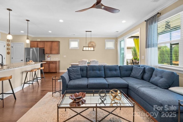 living room with crown molding, ceiling fan, and dark wood-type flooring