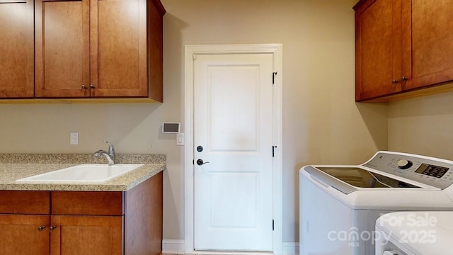 clothes washing area with washing machine and clothes dryer, sink, and cabinets