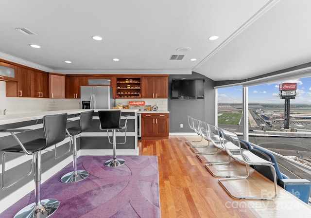 kitchen featuring ornamental molding, light hardwood / wood-style floors, stainless steel fridge with ice dispenser, and tasteful backsplash