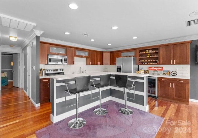 kitchen featuring beverage cooler, stainless steel appliances, a center island, a breakfast bar area, and light hardwood / wood-style floors